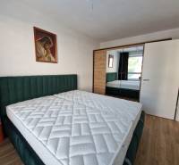 Bedroom in a two-room apartment with a double bed, painting, and built-in wardrobe.