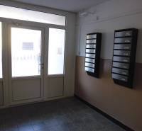 Entrance to an apartment building with mailboxes and glass doors.