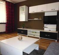 Living room in a three-room apartment with a furniture wall and decorations on the shelves.