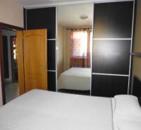 Wardrobe in the bedroom of a 3-room apartment with a bed and a mirror on the door.