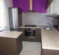 A kitchen with stainless steel appliances and a purple wall in a 3-room apartment.