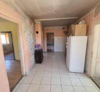 A hallway in a family house with older furnishings and appliances, in need of renovation.