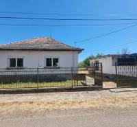 A family house in Ipolyvec with a fence, garage, and garden, the sky is clear.