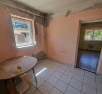 A room in a family house with a window, visible are worn-out walls and an old table.