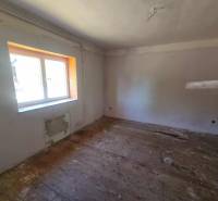 A room in a family house with a wooden floor and a large window.