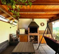 Covered terrace with a fireplace and a swing in a family house.