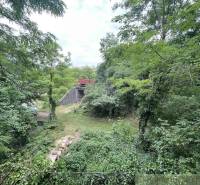 Greenery surrounds the stone structure near the family house in Branč.