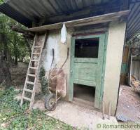 A dilapidated shed with wooden doors and a ladder on the property of a family house in Branč.