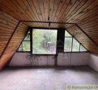 Attic room with wooden paneling and a view of the garden in a family house.