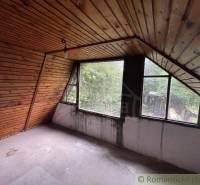 Attic room in a family house with wooden paneling and large windows.