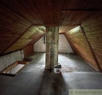An attic with wooden paneling and a concrete floor in a family house.