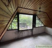 Attic room in a family house with wooden paneling and a view of the garden.