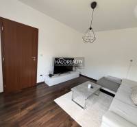 A living room in a family house with a dark floor, a white sofa, and a TV stand.