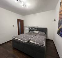 Bedroom in a family house with a bed, dark floor, and a picture on the wall.