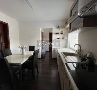 A furnished kitchen and a dining table with black chairs in a family house.