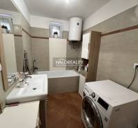 A bathroom in a family house with a shower, washing machine, and sink.