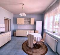 A kitchen in a family house with a dining table, kitchen unit, and refrigerator.