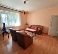 Living room of a family house with a sofa, armchairs, a television, and a wooden table on a carpet.