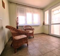 Two wicker chairs with cushions in a sunlit room of a family house.