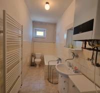 A bathroom in a family house with a bathtub, toilet, and sink in light shades.