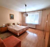 A bedroom in a family house with a double bed, a painting, and a large window.