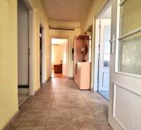 A hallway of a family house with tiles, doors, and storage furniture.