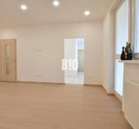 A bright room with wooden flooring in a 3-room apartment, illuminated by ceiling lights.
