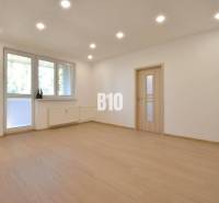 Living room with parquet flooring and white walls in a three-room apartment.