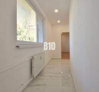 A hallway in a 3-room apartment with marble flooring and a window with a view.