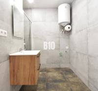 A bathroom in a 3-room apartment with a sink and a boiler, light tiles dominate the space.