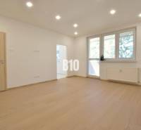 A bright room in a 3-room apartment with wooden flooring and a large window.