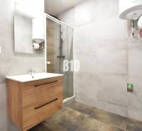 A bathroom in a 3-room apartment with a wooden cabinet, a shower corner, and a water heater.