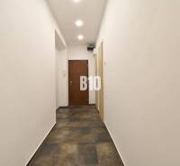 A hallway with white walls and a dark floor in a 3-room apartment.