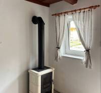 A bathroom in a family house with a tiled floor and a window with sheer curtains.