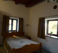 A bedroom in a family house with a wooden bed, a window, and curtains.