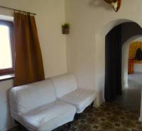A family house with a white sofa, decorated floor, and arched passage.