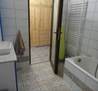 A family house bathroom with a bathtub, a sink, and patterned tiles.