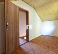 A room in a cottage with wooden doors and a wooden floor.
