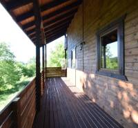 Wooden terrace of the cottage in Bytča with a view of greenery and forests.