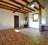 Interior of a cabin with a wooden ceiling, floor, and stove.