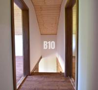 A wooden attic with a hallway in the cottage, with a natural ceiling and floor.
