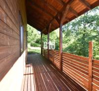 A wooden terrace of a cottage in Bytča surrounded by greenery and forest scenery.