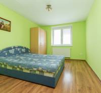 A bedroom with green walls, a double bed, and wooden flooring in a two-room apartment.