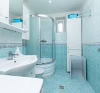 The bathroom in the 2-room apartment has a shower, a sink, cabinets, and white tiles.