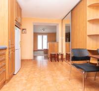 A kitchen and dining room in a 2-room apartment with wooden furniture and ceramic tiles.