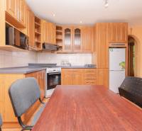 A kitchen in a 2-room apartment with a wooden kitchen unit and a dining table.