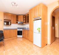 A kitchen in a 2-room apartment with a wooden cabinet, a microwave, and a stove on tiles.