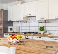 A kitchen in a family house with light cabinets, a wooden countertop, fruit, and herbs.