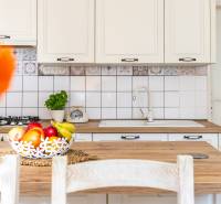 A kitchen in a family house, white cabinets, wooden countertop, a basket of fruit.