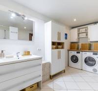 A spacious bathroom with a washing machine and dryer in a family house, with a bright interior.